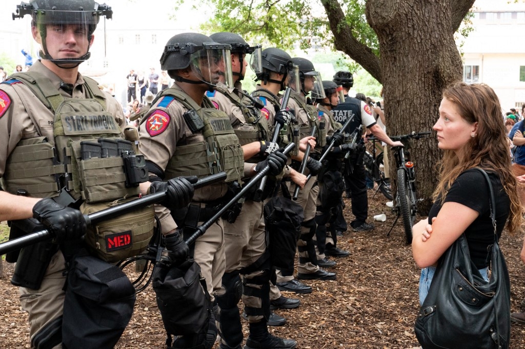 Une étudiante regarde une rangée de soldats de l’État du Texas alors que des étudiants propalestiniens manifestent contre la guerre sur le campus de l’université du Texas à Austin, aux États-Unis, le 24 avril 2024 (Suzanne Cordeiro/AFP)