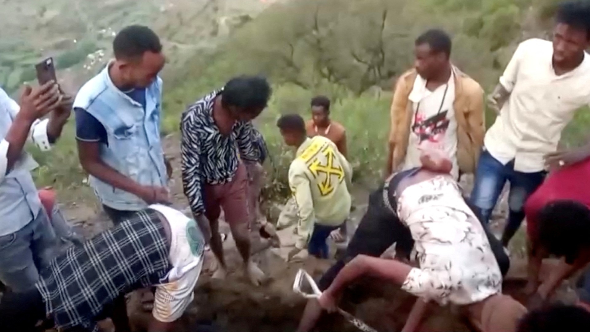 Migrants dig a grave near the trail from Al Thabit into Saudi Arabia, on the Yemen side