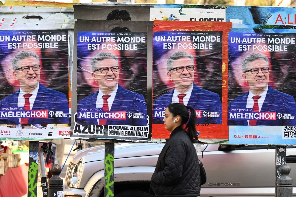 A woman walks past posters for French leftist presidential candidate Jean-Luc Melenchon in Marseille, southern France, on 31 March 2022 (AFP)