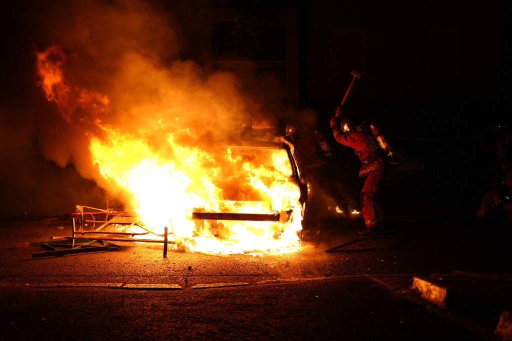 Un pompier tente de maîtriser l’incendie d’un véhicule brûlé par des manifestants en colère à Nanterre, le 27 juin 2023, après la mort d’un jeune automobiliste tué par la police (AFP/Zakaria Abdelkafi)