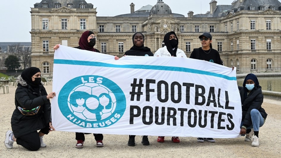 Women pose with a banner reading “football for all” to protest a ban on wearing religious symbols, such as the hijab, in sports competitions in Paris in January 2022 (Bertrand Guay/AFP)