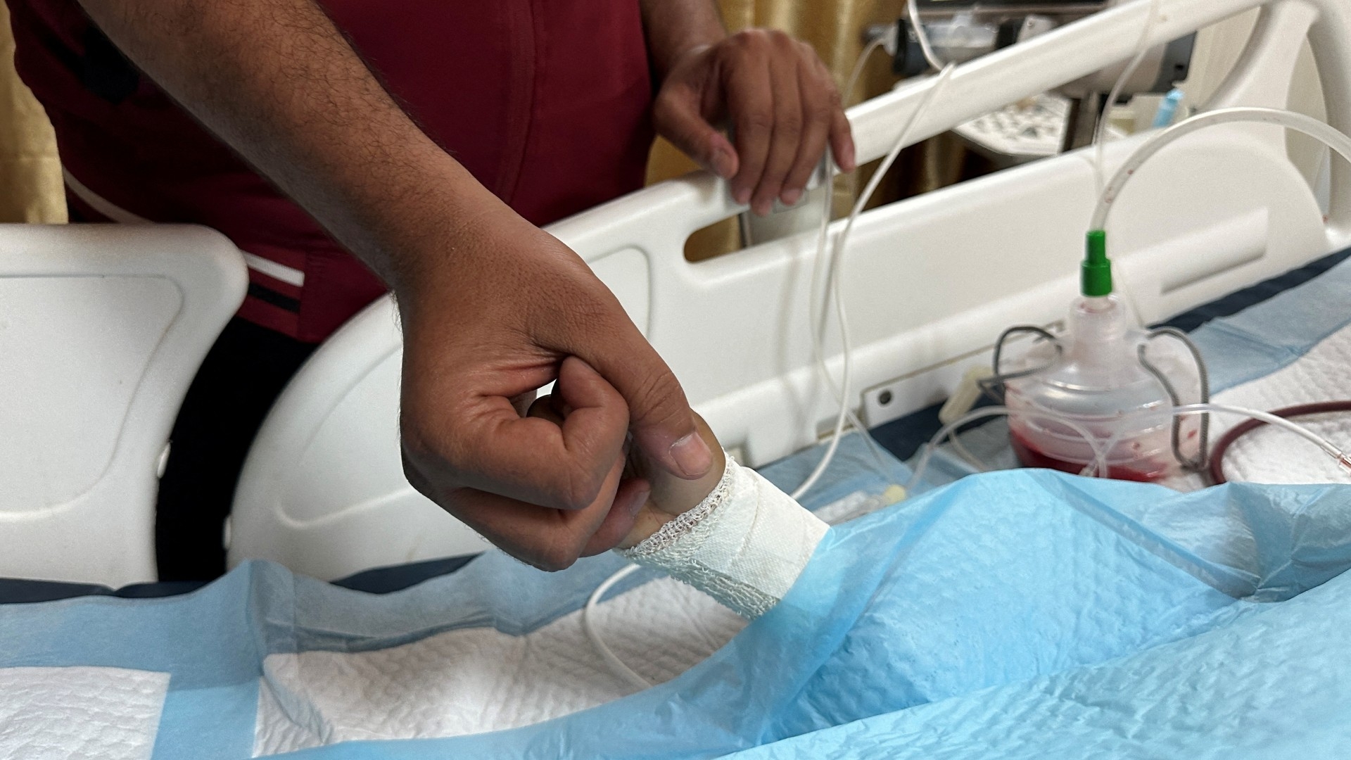 A father holds the hand of his injured child in al-Aqsa Martyrs Hospital in Deir al-Balah, 9 June (Reuters/Doaa Rouqa)