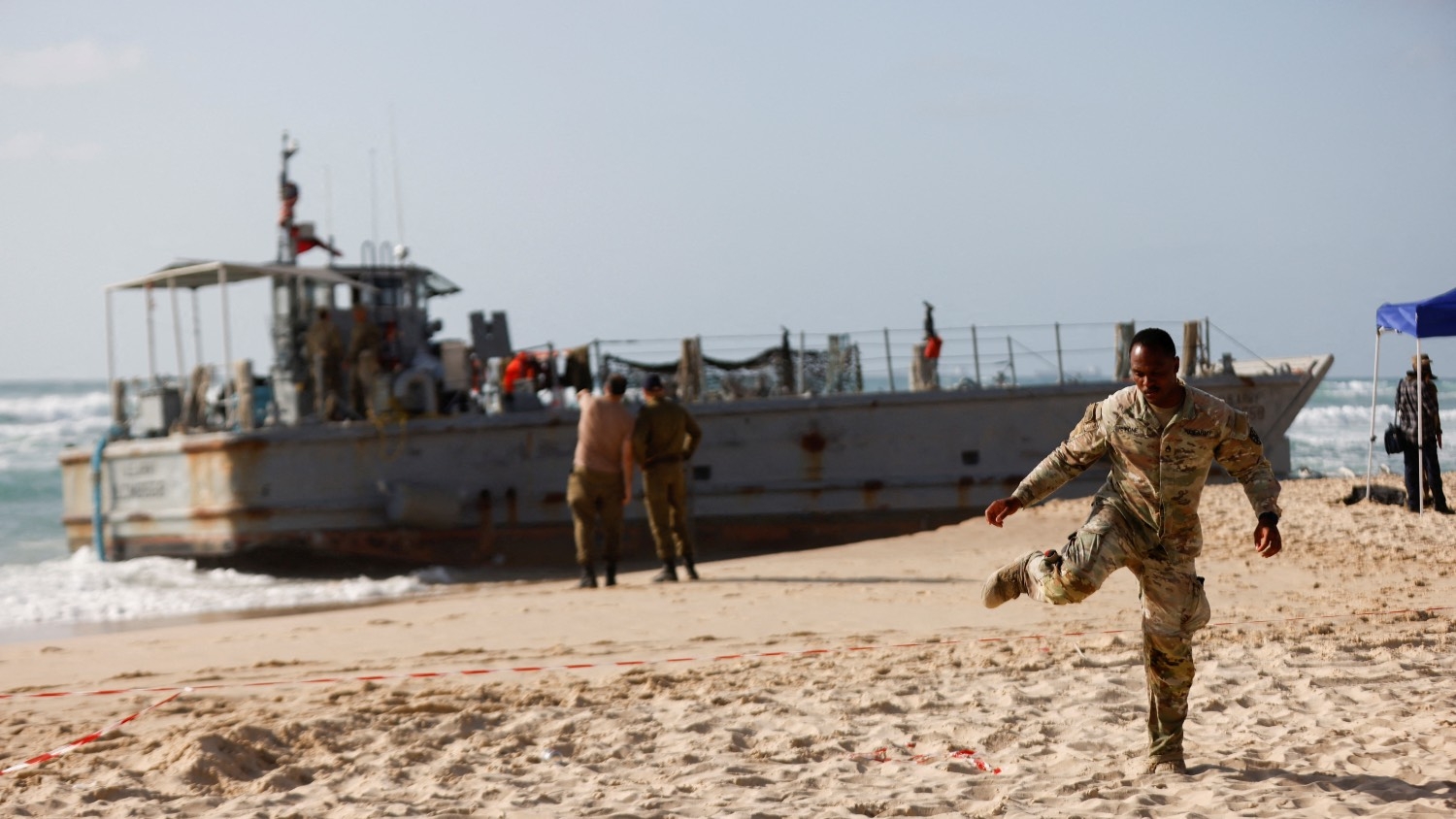 A US soldier leaves a cordoned-off area as other troops work on a beached vessel used for delivering aid to Palestinians via the US-built pier in Gaza on the Mediterranean coast in Ashdod, Israel on 25 May 2024.