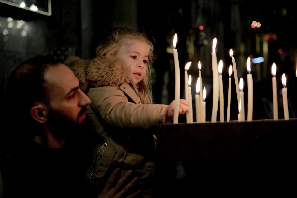 Un enfant palestinien allume des bougies lors d’une messe à l’église orthodoxe grecque Saint-Porphyre dans la ville de Gaza, le 7 janvier 2024, alors que l’offensive israélienne se poursuit à Gaza (AFP)