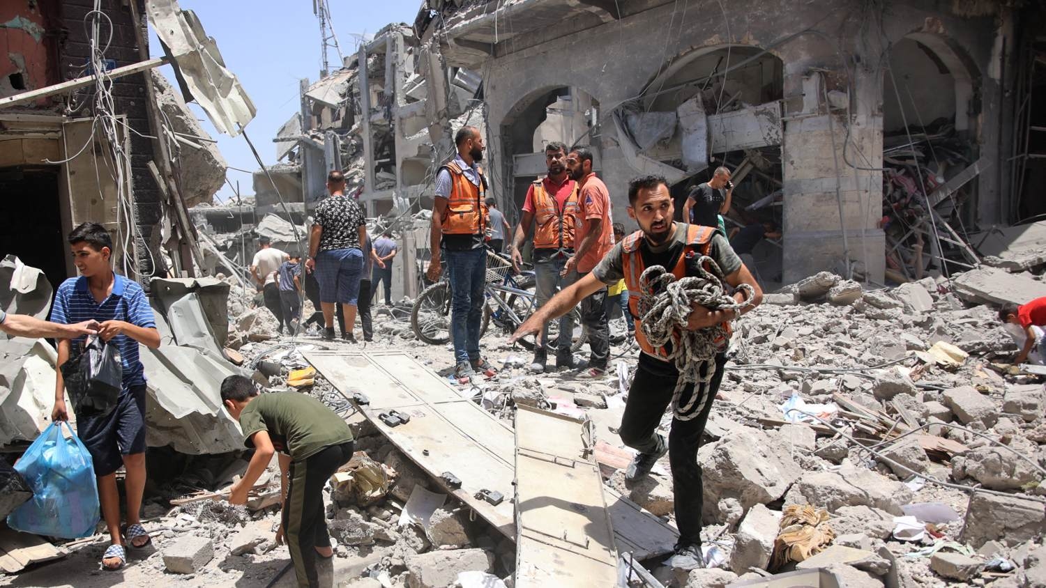 Palestinian rescuers stand on the rubble of destroyed buildings following Israeli bombardment near the Great Omari Mosque in the Old City of Gaza City on 4 July 2024 (Omar al-Qattaa/AFP)