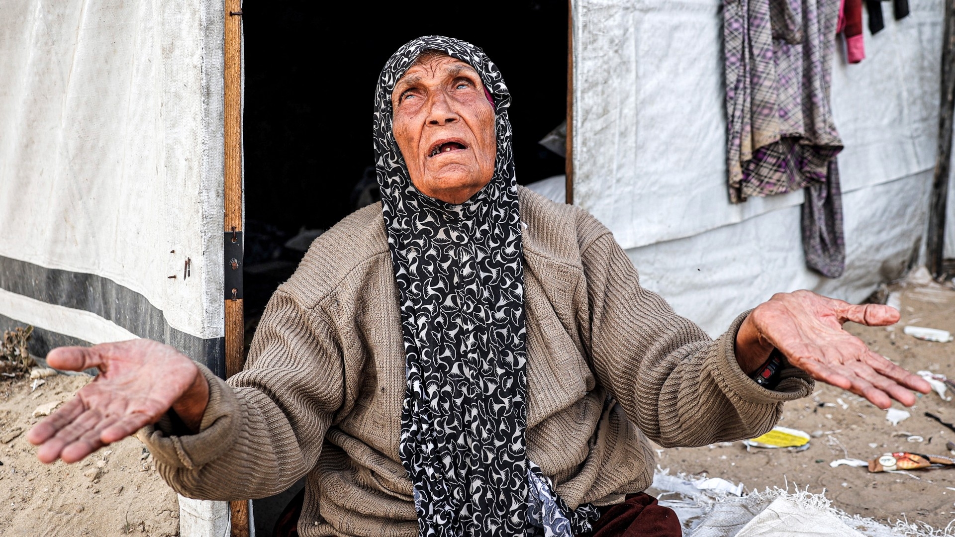 An elderly woman reacts as she sits outside a tent at a camp for displaced Palestinians in Rafah in the southern Gaza Strip on 30, April, 2024 (AFP) 