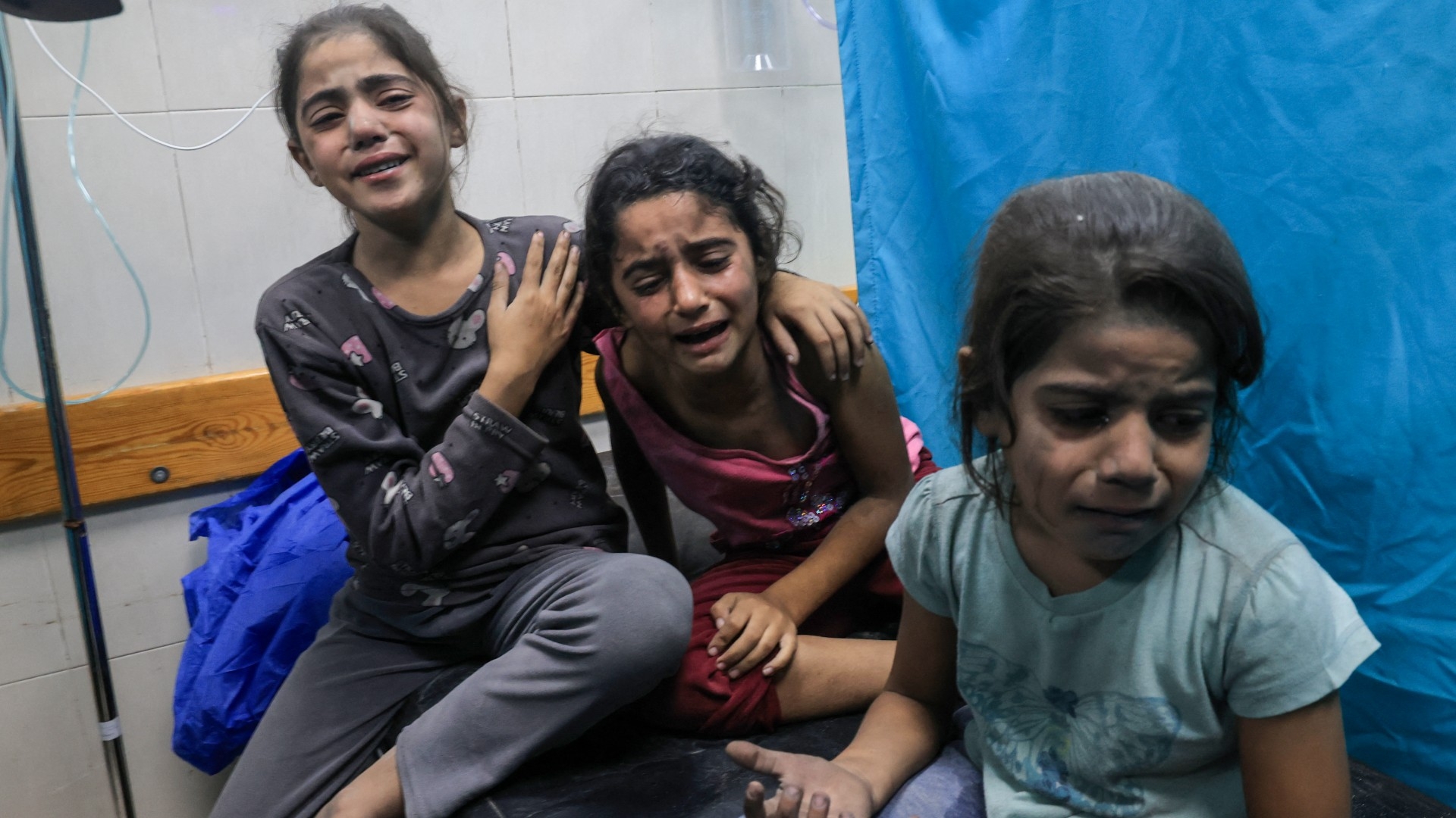 Palestinian children injured in an Israeli air strike await treatment at the Nasser hospital in Khan Yunis in southern Gaza, on 17 October 2023 (AFP)