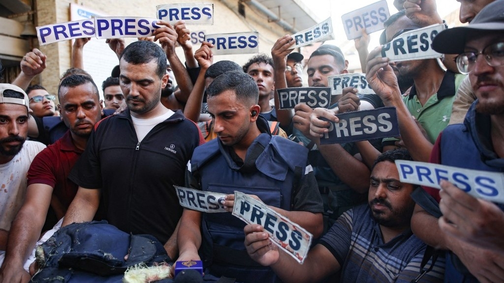 Mourners and colleagues holding 'press' signs surround the body of Al Jazeera journalist Ismail al-Ghoul, killed along with his cameraman Rami al-Refee in an Israeli strike in Gaza's al-Shati refugee camp, on 31 July (AFP)