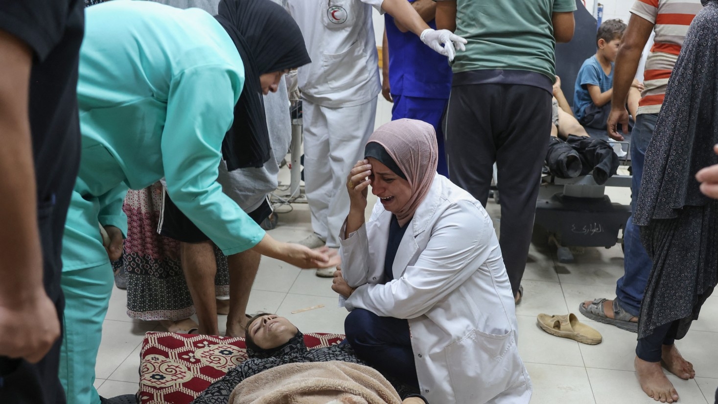 A Palestinian nurse weeps as she tends to a wounded woman following Israeli bombardment of a displacement camp in Khan Yunis, at the main hall of the Nasser hospital on 1 October 2024 in the southern Gaza Strip city (AFP)