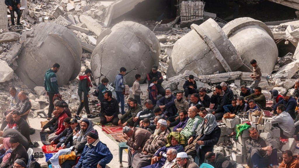 Palestinians attend the Friday noon prayers in front of the ruins of the al-Faruq mosque, destroyed in Israeli strikes in Rafah in the southern Gaza Strip on 1 March 2024 (AFP)
