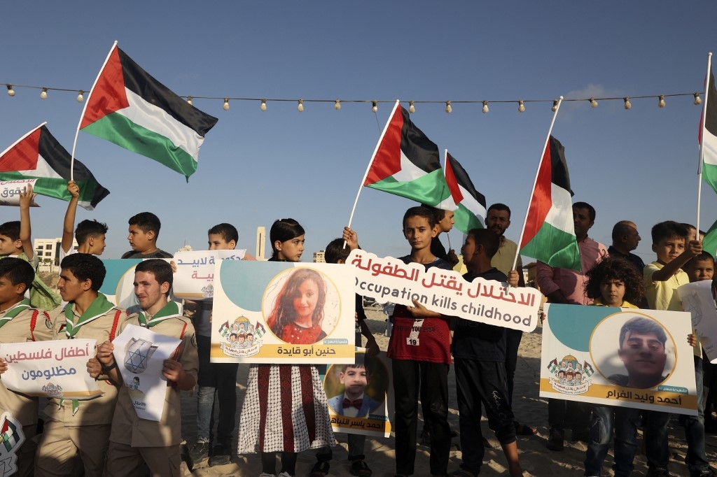 Scouts carrying Palestinian flags and pictures of children who were killed during the latest round of conflict between Israel and Gaza gather for a commemorative event, on 17 August 2022 (AFP)