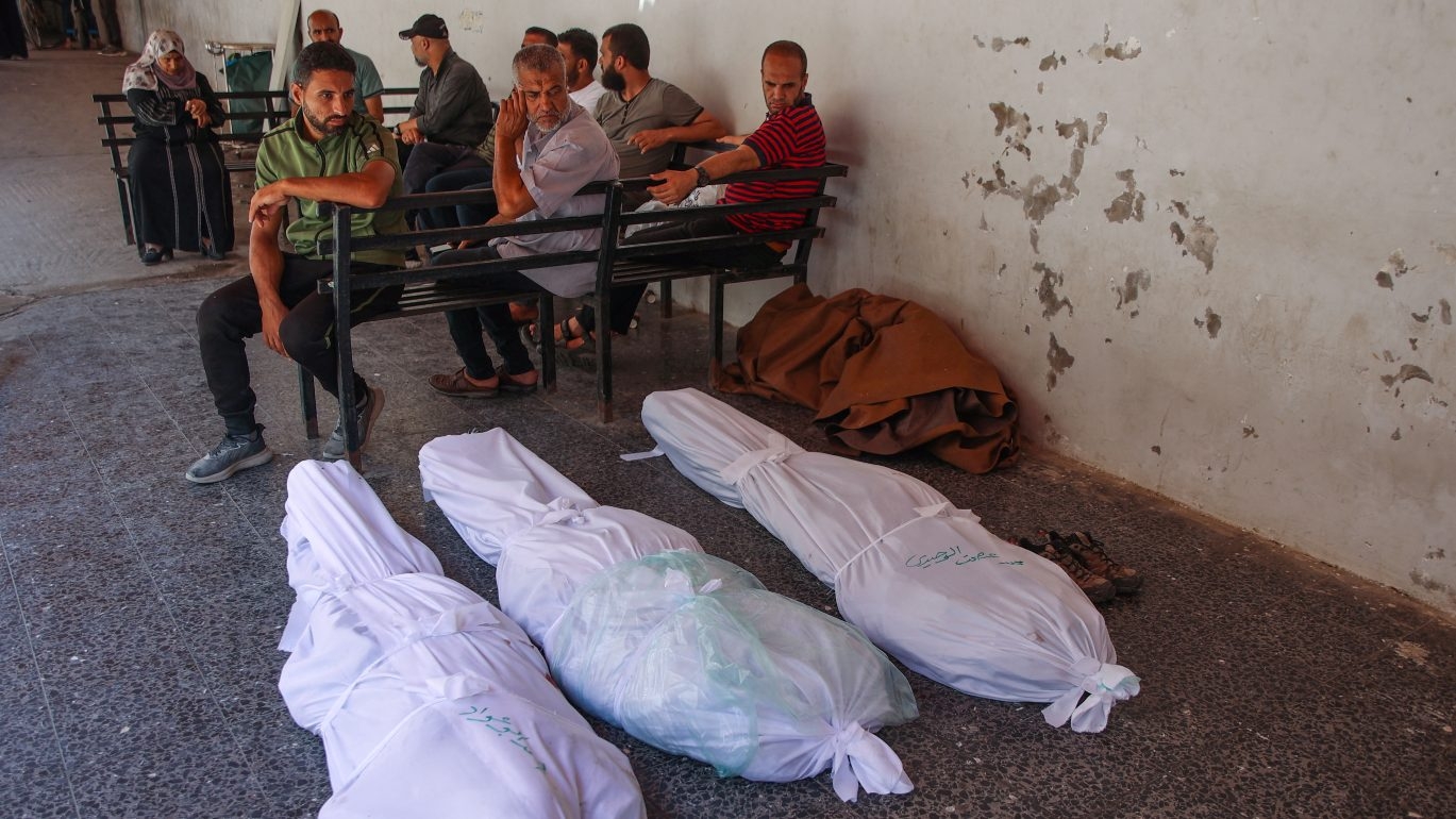 Palestinians look at the shrouded bodies of people reportedly killed in an Israeli strike on the western Rimal neighbourhood on 5 June 2024.