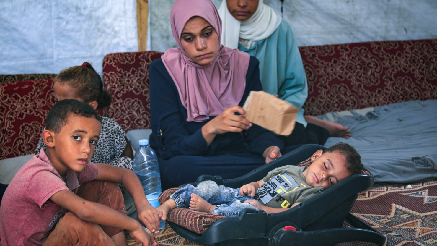 Abdel Rahman Abu al-Jedian who contracted polio a month ago sleeps surrounded by family members in Deir al-Balah, central Gaza, on 27 August 2024 (Eyad Baba/AFP)