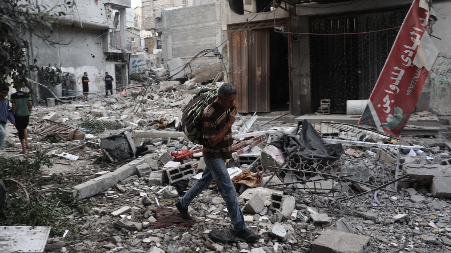 People carry salvaged items amid the rubble of buildings damaged during an Israeli air strike the previous night on the Bureij refugee camp in the central Gaza Strip on 8 October 2024.