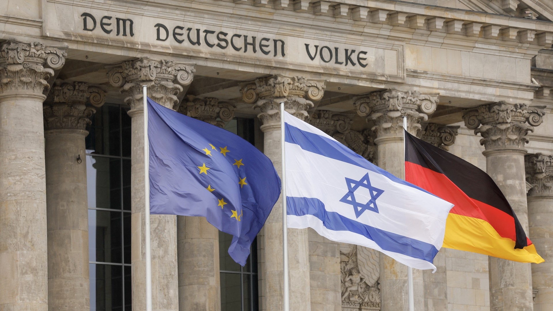 The EU, Israeli and German flags in front of the Bundestag, the German lower house of parliament in Berlin, on 12 October 2023 (AFP/Odd Andersen)