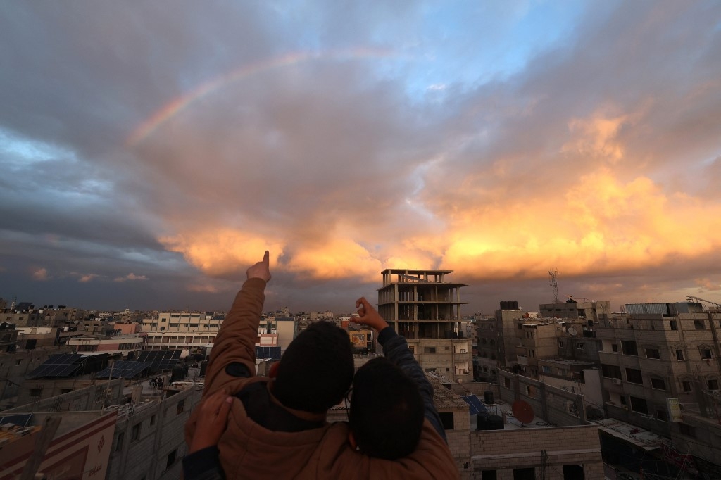Des enfants regardent un arc-en-ciel au-dessus de Rafah, alors qu’Israël continue ses raids sur la bande de Gaza (AFP)