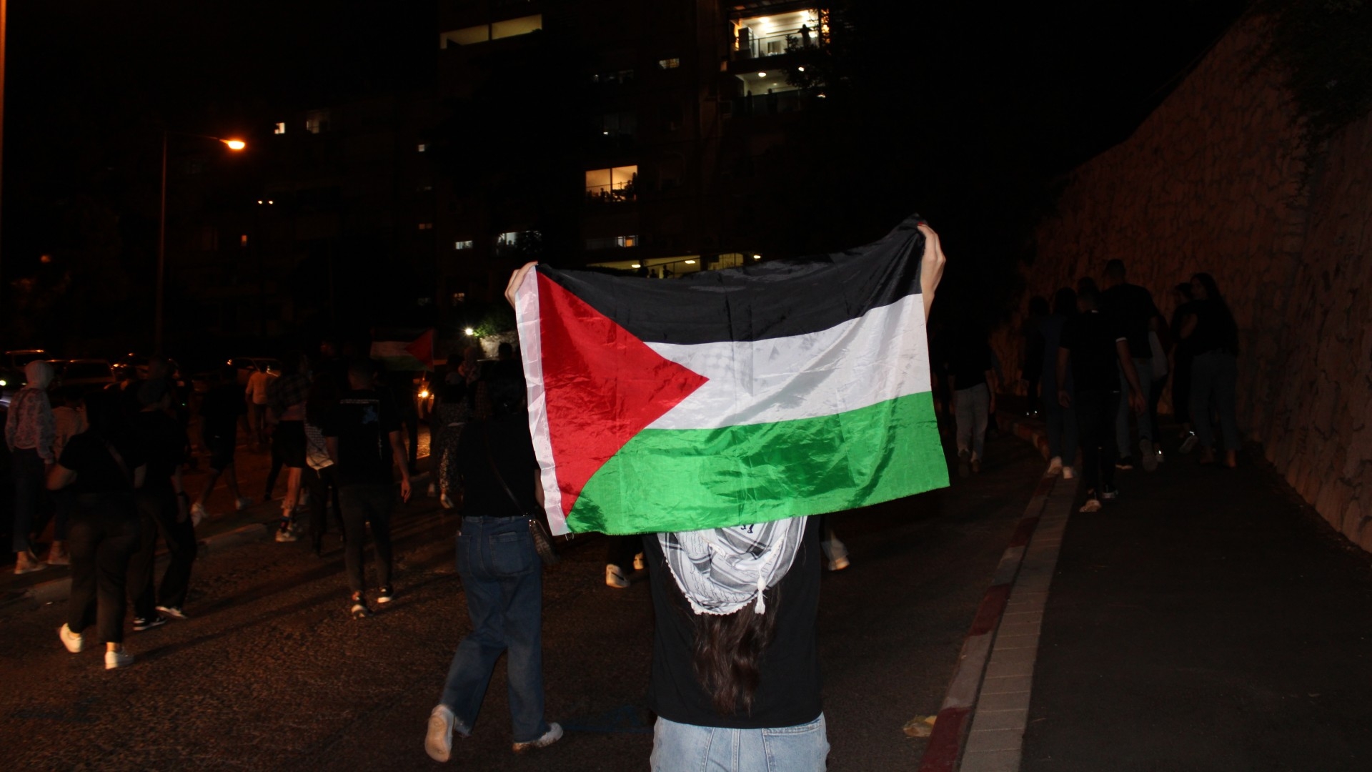 A protester in Haifa holds up a Palestinian flag (MEE/Vera Sajrawi)