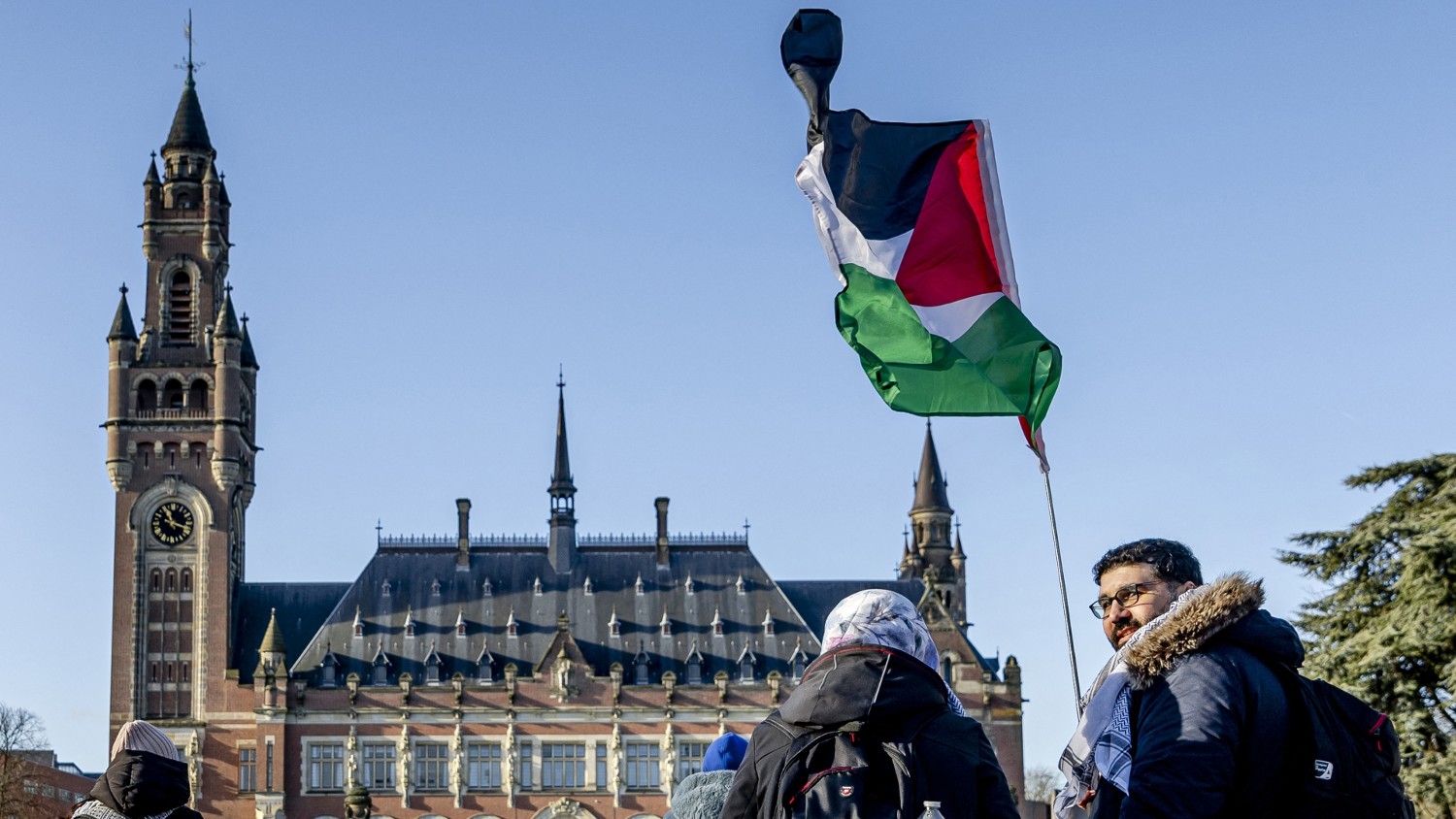 A demonstrator waves the Palestinian flag in front of the Peace Palace ahead of the International Court of Justice (ICJ) verdict in the genocide case against Israel on 26 January 2024.