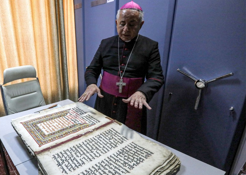 L’archevêque chaldéen de Mossoul Michaeel Najeeb présente un ancien codex chrétien en langue syriaque au Centre numérique des manuscrits orientaux à Erbil, le 16 mai 2023 (AFP/Safin Hamid)