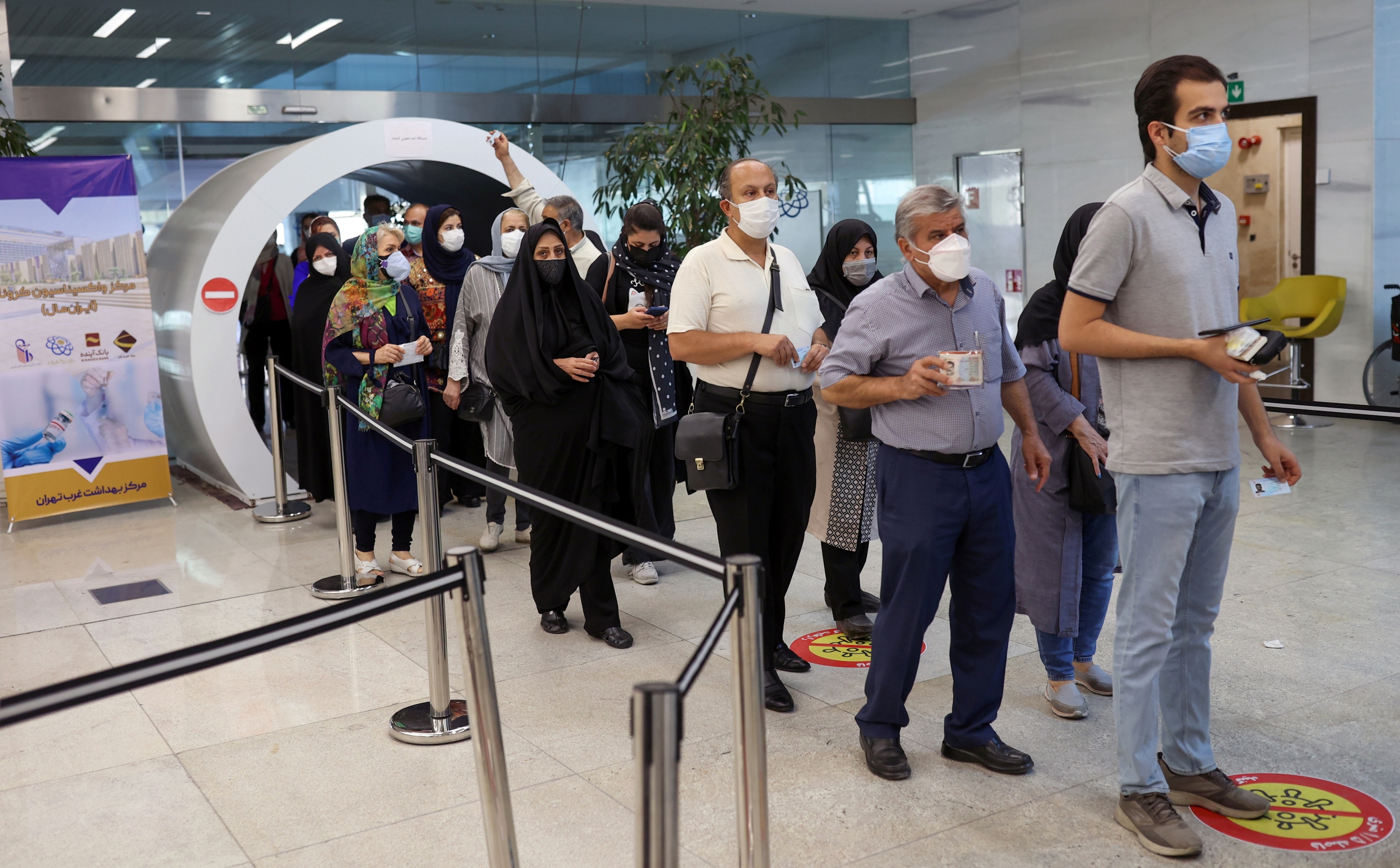 Iranians wait in a queue to receive a vaccine against Covid-19 as cases spike, in a vaccination center in Tehran on 9 August 2021.