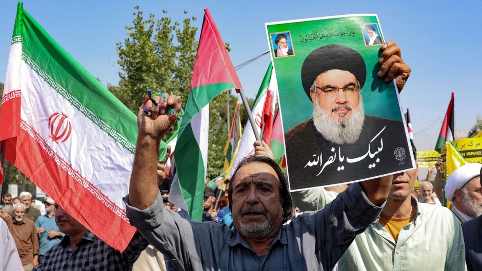 A man raises a picture of slain Hezbollah chief Hassan Nasrallah during an anti-Israel protest in Tehran on 27 September 2024 (AFP)