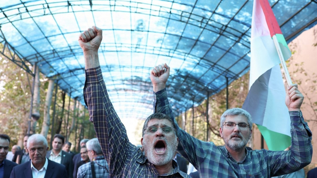 Men shout slogans and hold up the Palestinian flag after the assassination of Hamas political leader Ismail Haniyeh on 31 July 2024, during a rally at Tehran University in the Iranian capital (AFP)