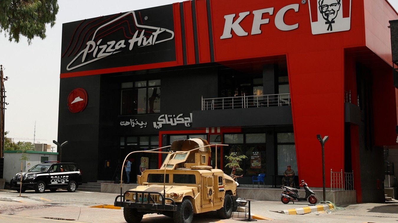 Iraqi security forces vehicles are stationed in front of a Kentucky Fried Chicken (KFC) and Pizza Hut fast food restaurants in the Al-Jadriya neighbourhood in Baghdad on 30 May 2024.