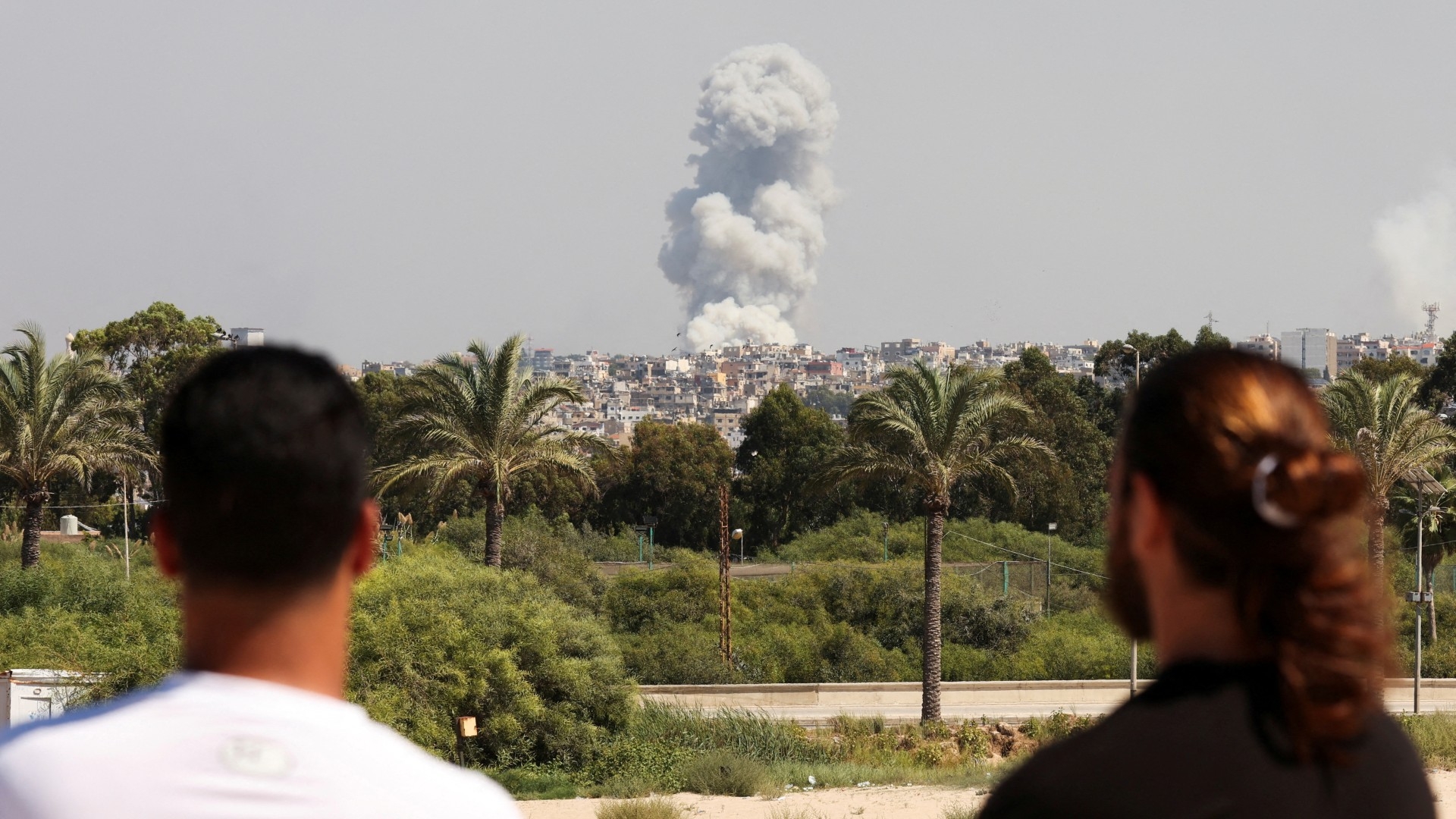 People watch as smoke billows over southern Lebanon following Israeli strikes, as seen from Tyre, southern Lebanon 23 September (Reuters/Aziz Taher)