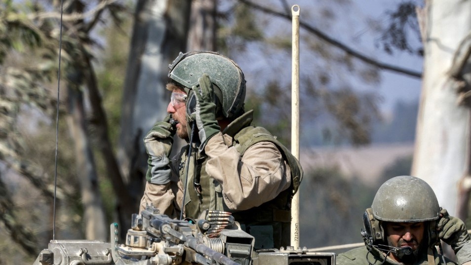 An Israeli soldier uses a radio while sitting in the turret of a main battle tank at a position along the border with the Gaza Strip and southern Israel on 14 July 2024 (AFP)