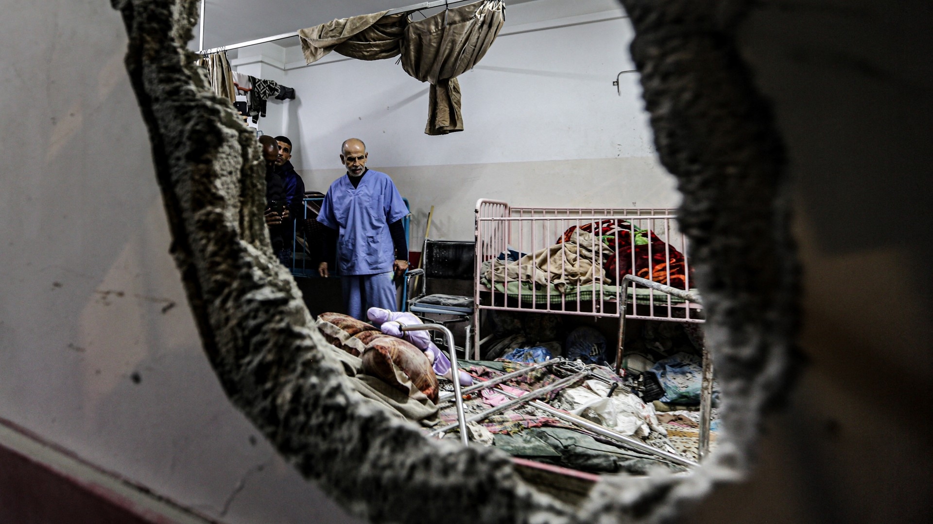People inspect the damage in a room following Israeli bombardment at Nasser hospital in Khan Yunis in the southern Gaza Strip on 17 December 2023 (AFP)