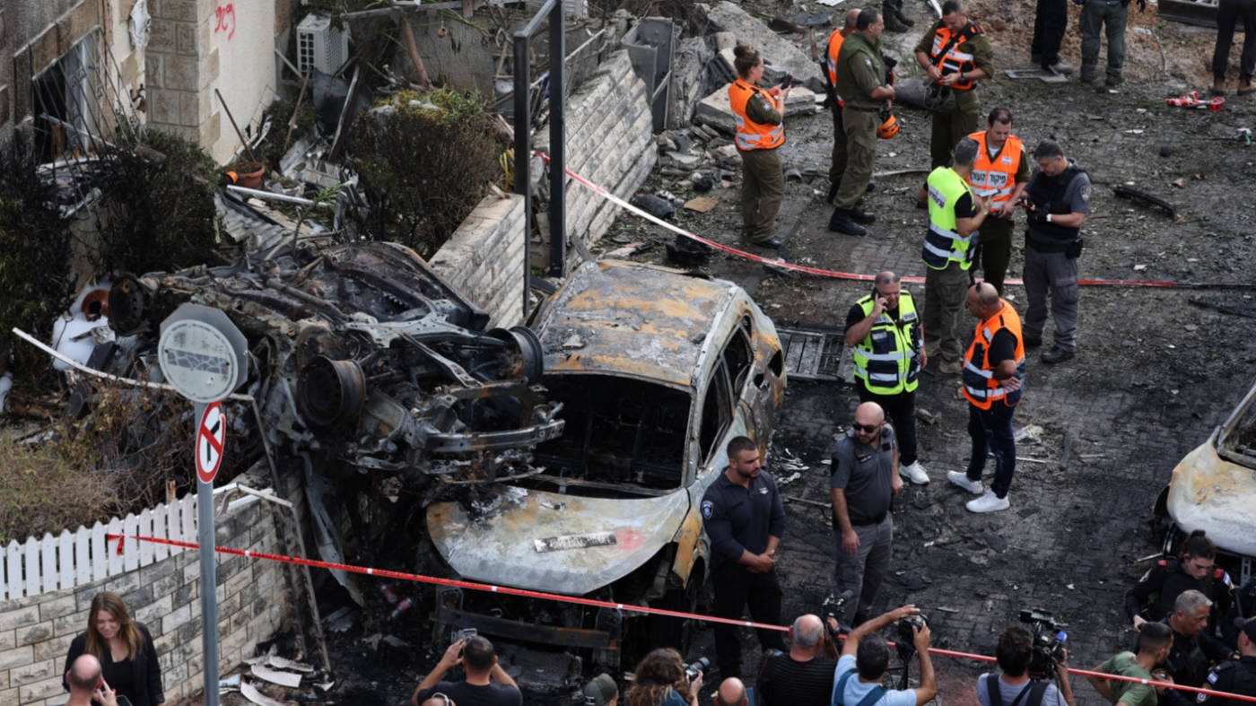  Israeli forces gather amid debris and charred vehicles in Kiryat Bialik, Israel, following a rocket strike by Hezbollah in September 2024 (AFP)