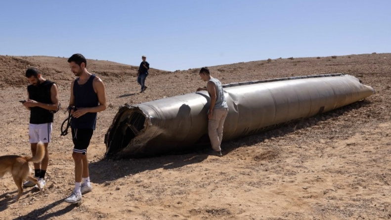 People visit the site of an Iranian missile’s remains in the Negev desert near Arad on 3 October 2024, following an Iranian missile attack on Israel (Menahem Kahana/AFP)