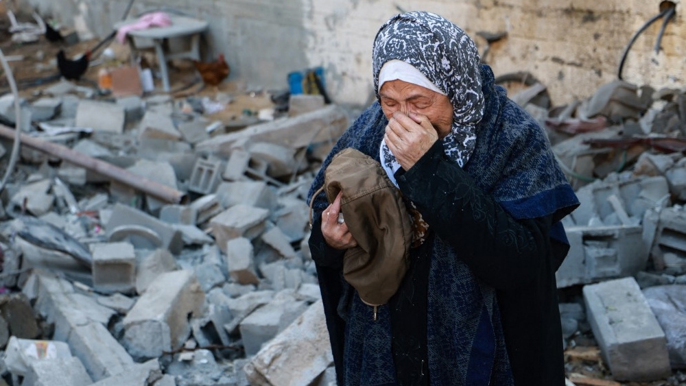 A woman reacts after finding clothing of a killed relative in the rubble of a house destroyed in Israel’s bombing of Rafah, in the southern Gaza Strip, on 3 February 2024 (Mohammed Abed/AFP)