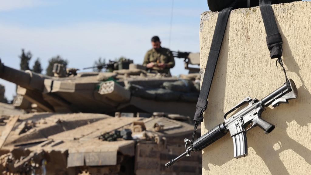 The rifle of an Israeli soldier hangs on a wall near the border with the Gaza Strip on 1 February 2024 (Jack Guez/AFP)