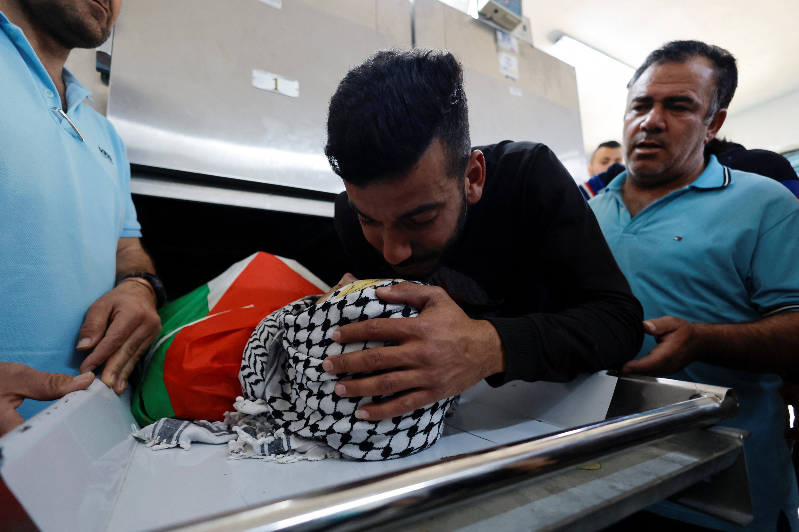 A mourner kisses the body of Palestinian Mohammad Ghoneim who was killed by Israeli forces in Bethlehem on 11 April 2022. (Reuters)