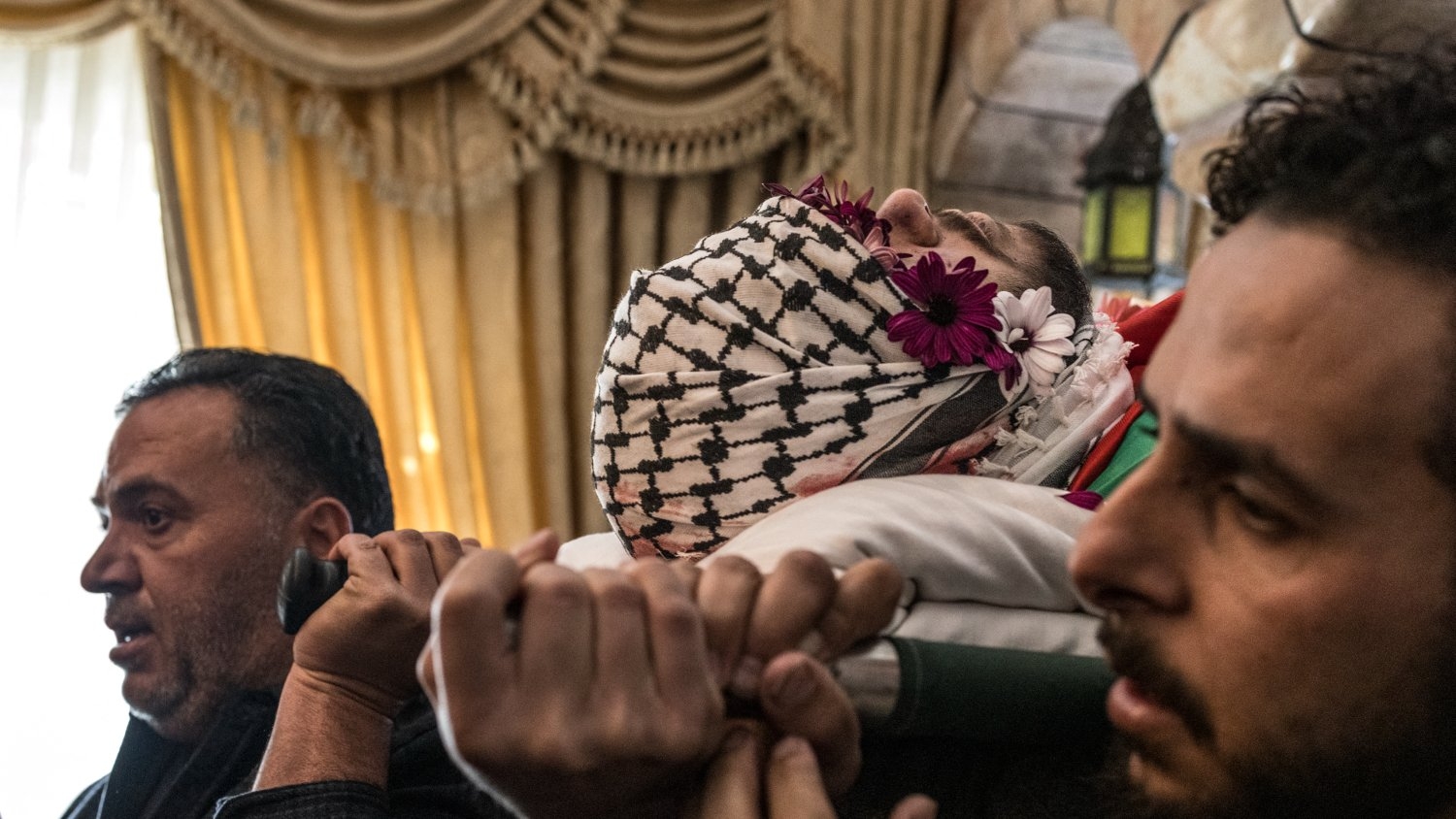 Mourners carry the flag-draped body of 17-year-old Palestinian Tawfiq Ajjaq ahead of his funeral procession on 20 January 2024.