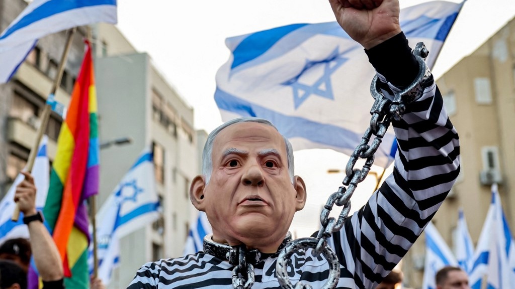 A protester wearing a costume depicting Israeli Prime Minister Benjamin Netanyahu in a prison uniform is pictured in Tel Aviv on 8 July 2023 (Jack Guez/AFP)