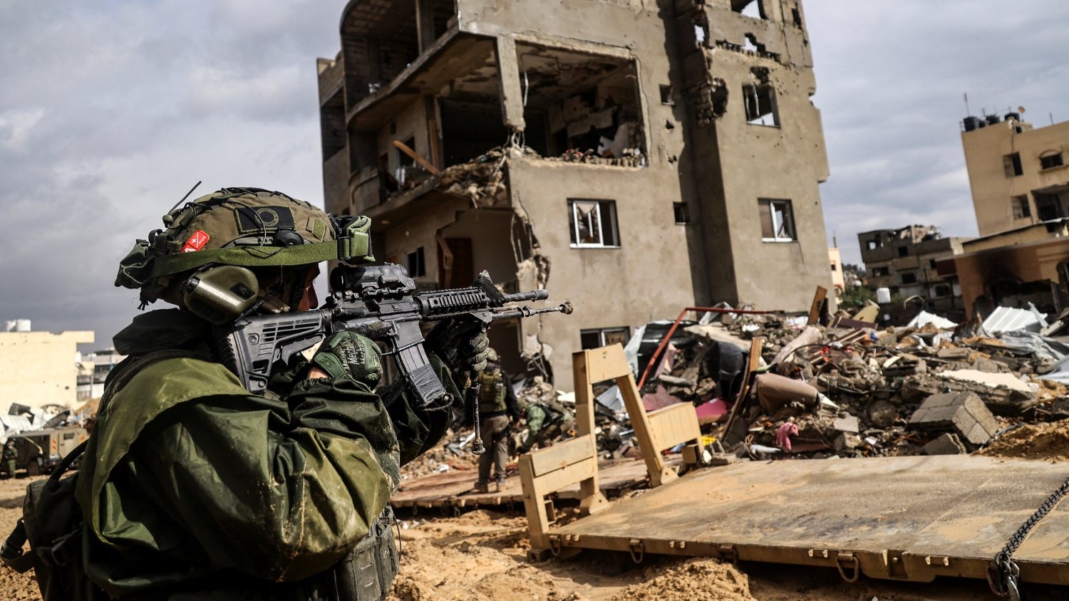An Israeli soldier aims his weapon in front of a destroyed building in Gaza's Khan Younis amid Israel's war on Gaza on 27 January 2024.