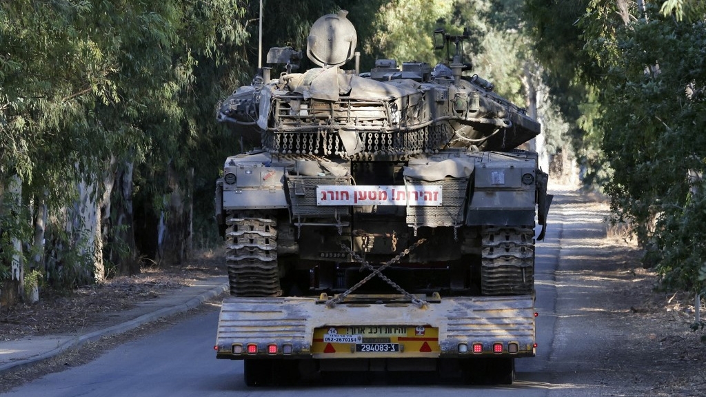 A lorry transports an Israeli battle tank near the border with Lebanon on 26 September 2024 (Jalaa Marey/AFP)