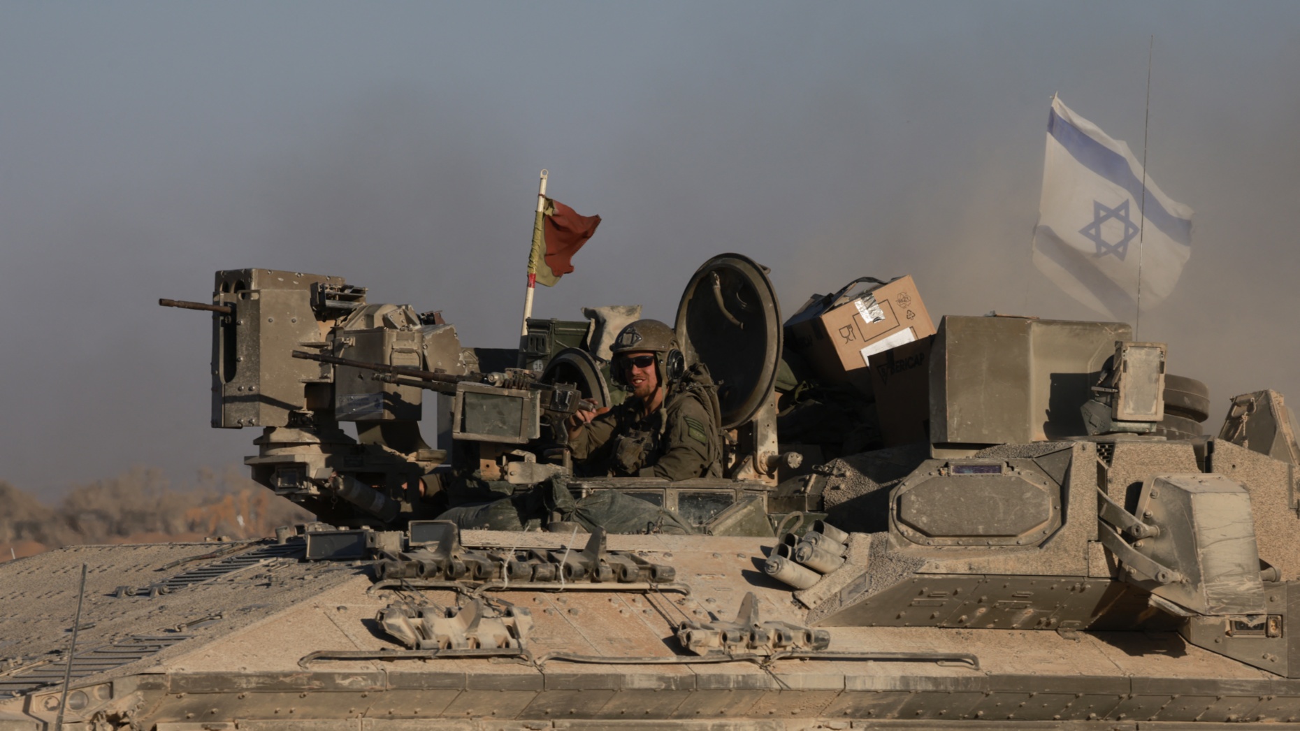 An Israeli soldier rides an armoured personnel carrier on the border with the Gaza Strip on 17 July 2024 (Menahem Kahana/AFP)