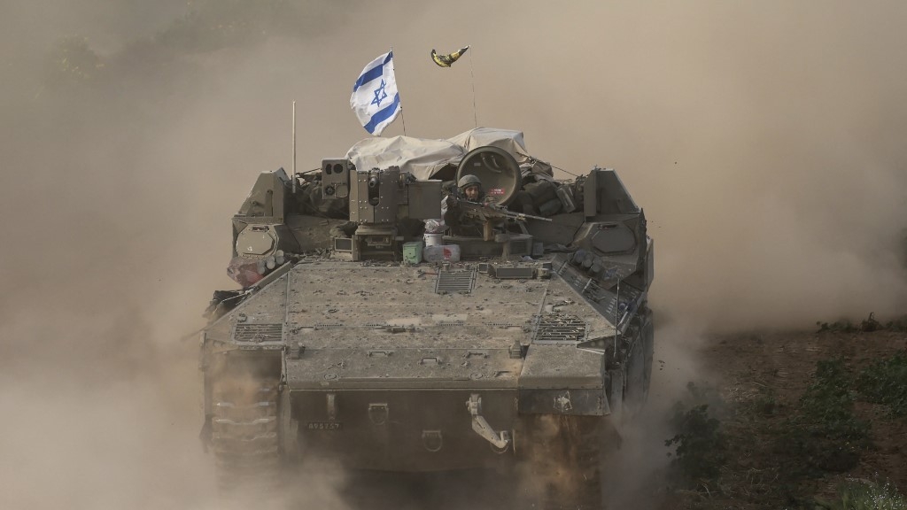 An Israeli soldier sitting on an armoured personnel carrier as it moves out of Gaza on 26 February 2024 (AFP)