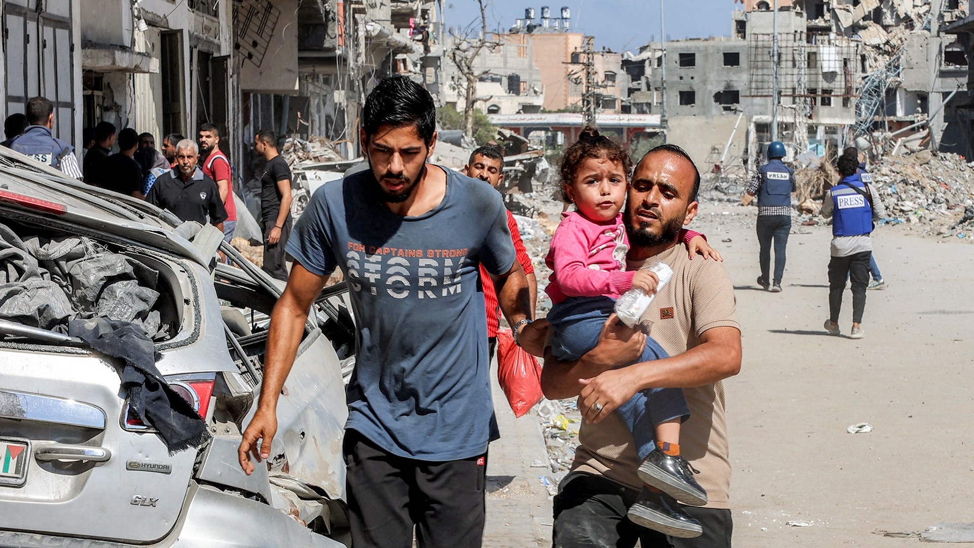 A man carries a child in the Jabalia camp for Palestinian refugees in the northern Gaza Strip on 9 October 2024 (AFP/Omar al-Qattaa)