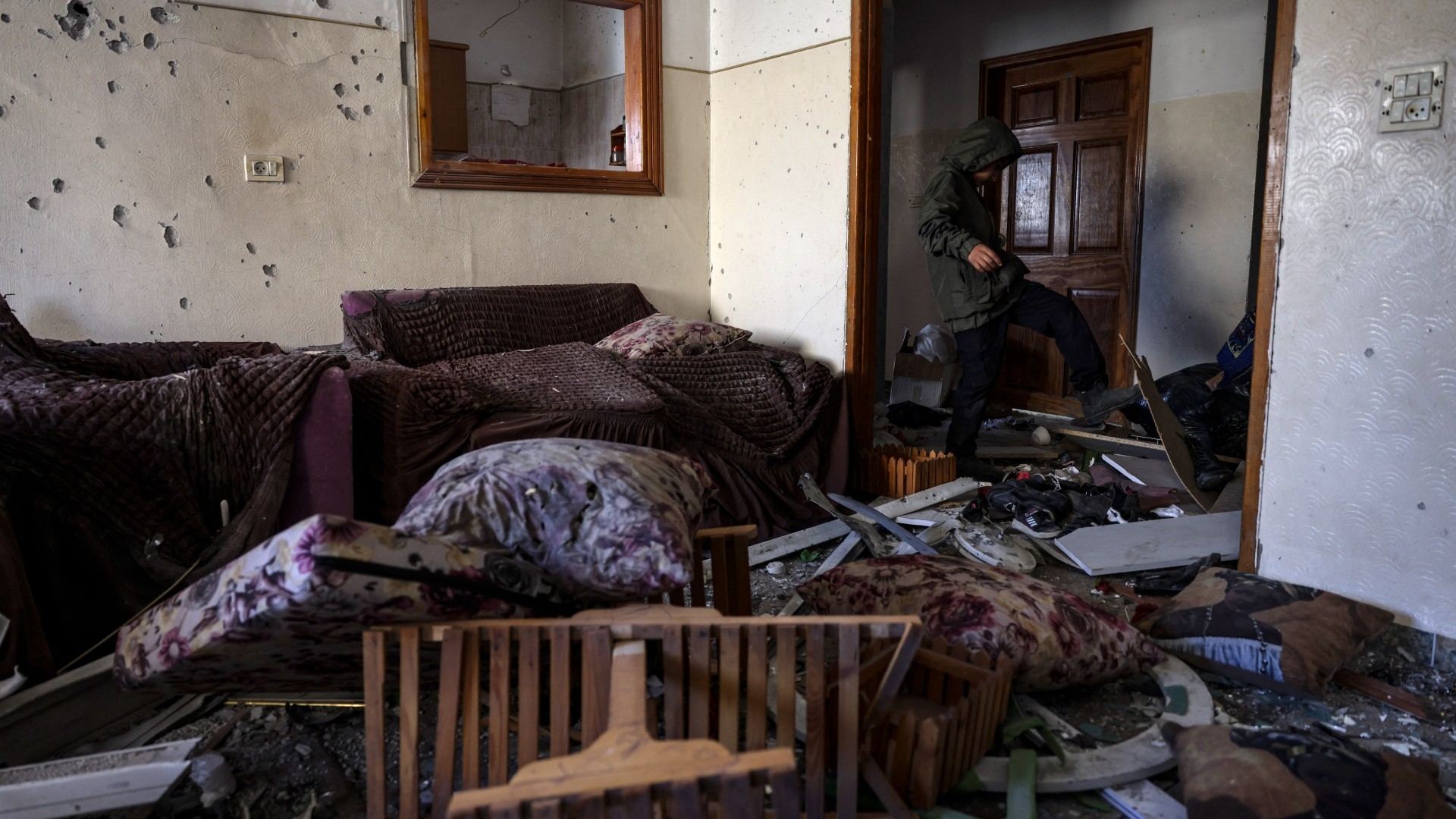 A Palestinian youth stands in a damaged room following an overnight Israeli raid on Jenin in the occupied West Bank on 21 February 2024 (AFP)