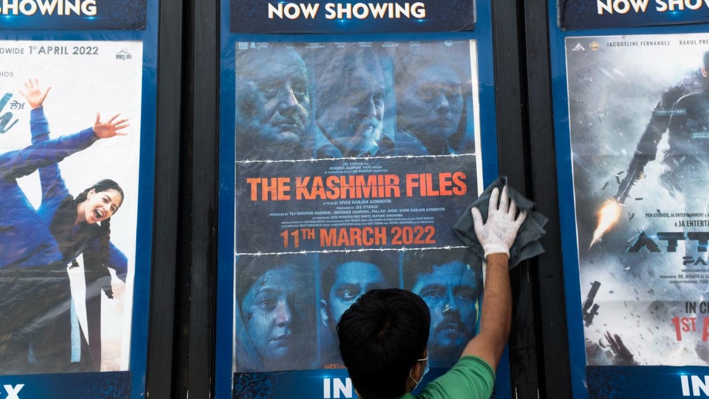 Un ouvrier nettoie un présentoir avec l’affiche du film The Kashmir Files devant un cinéma à New Delhi (AFP)