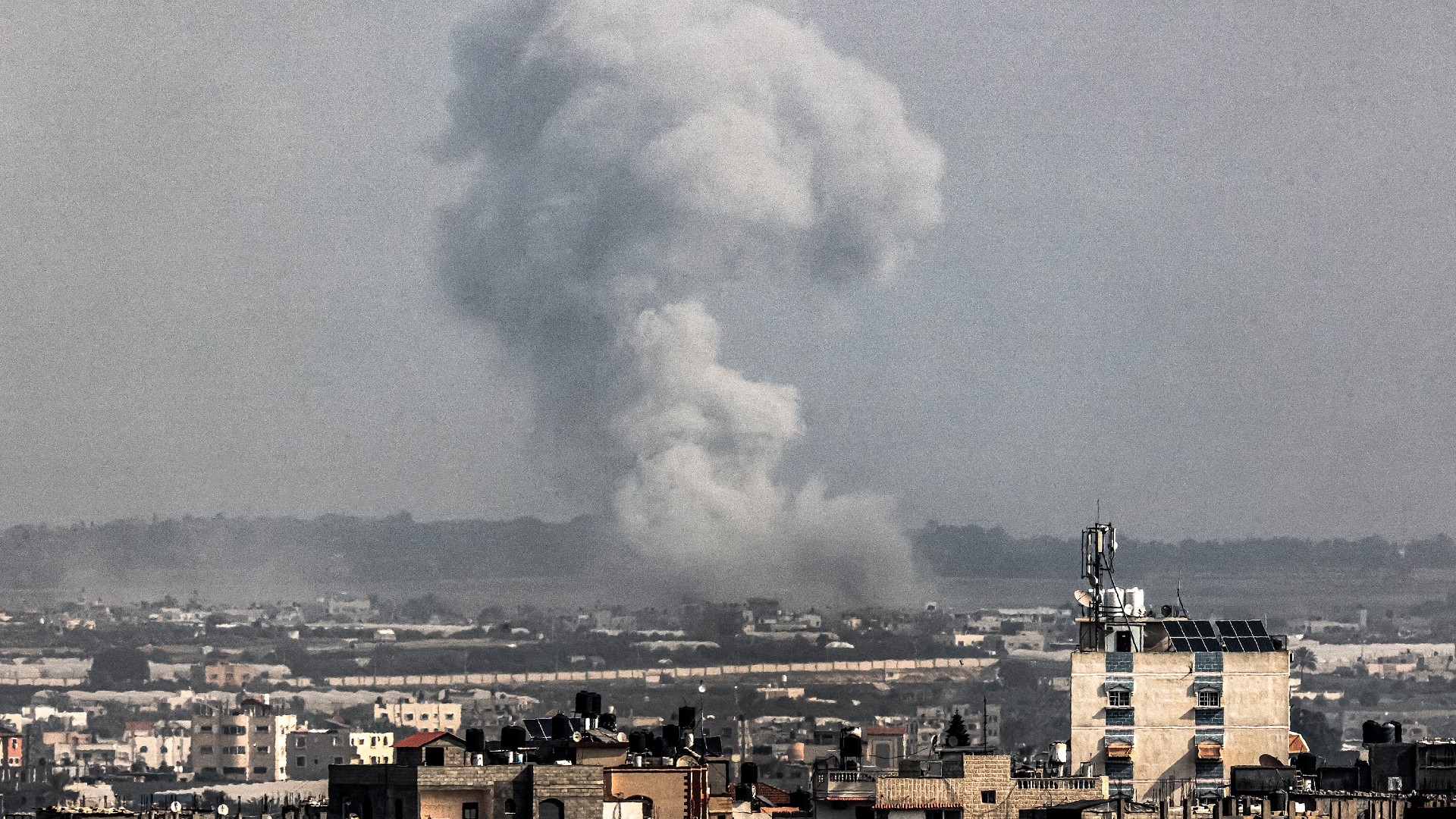 A smoke plume erupts over Khan Yunis from Rafah in the southern Gaza strip during Israeli bombardment on 27 December 2023 (AFP)