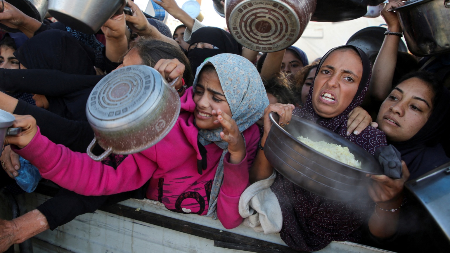 Palestinians gather to receive food cooked by a charity kitchen in Khan Younis, southern Gaza Strip on 19 November 2024 (Hatem Khaled/Reuters)