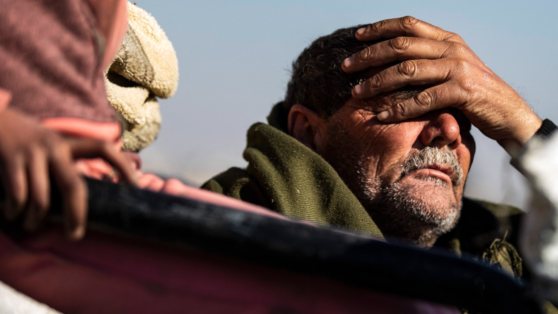 A Syrian Kurdish man, fleeing his home in the outskirts of Aleppo, reacts as he arrives to Tabqa on 2 December (Delil Souleiman/AFP)