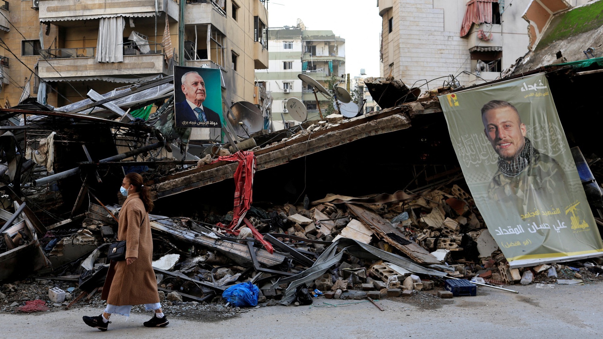 A woman walks past the rubble of a building in Beirut's southern suburbs, after the ceasefire between Israel and Hezbollah, 29 November (Reuters/Thaier Al-Sudani)