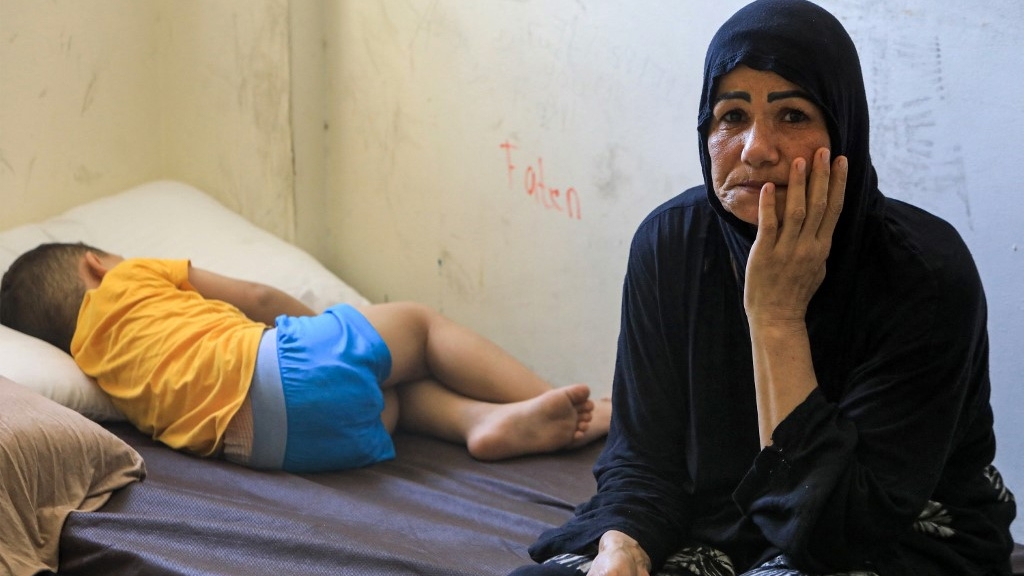 A child sleeps on a bed next to a woman at a shelter in Beirut, after their family was displaced by Israeli attacks from southern Lebanon, on 24 September 2024 (AFP)