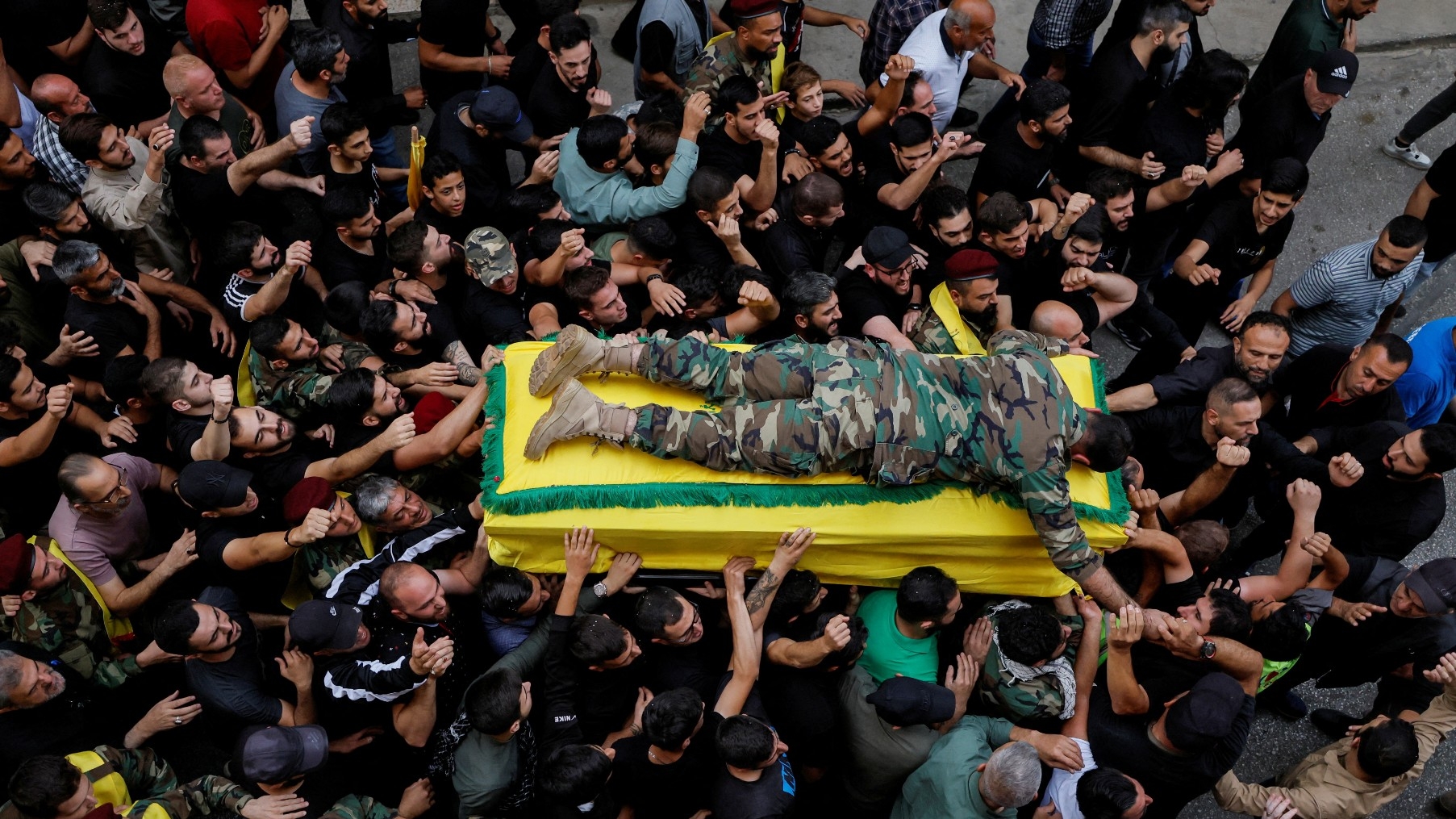 Nazih, son of Hezbollah member Mounir Youssef Achour, who was killed by Israel in southern Lebanon, lies on top of his father's coffin as he mourns him during his funeral, in Chaqra Lebanon, 30 October 2023 (Reuters)